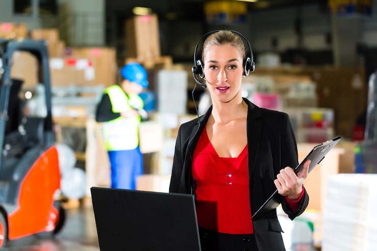 friendly-woman-dispatcher-supervisor-using-headset-laptop-warehouse-forwarding-company_79405-10230