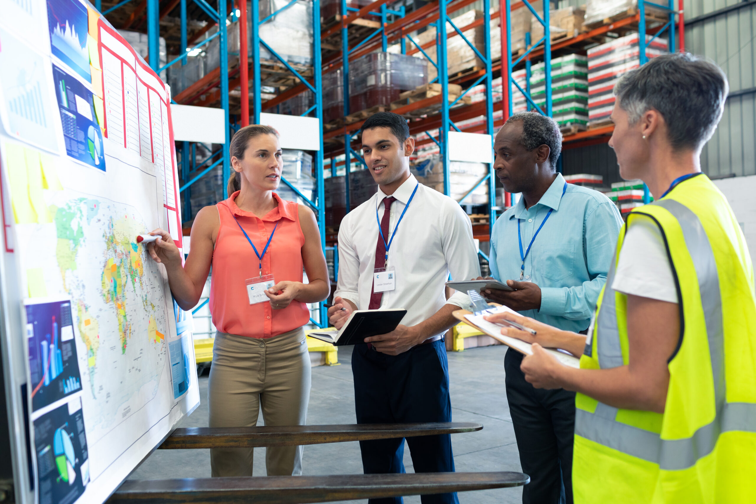 Front view of diverse warehouse staffs discussing over whiteboard in warehouse. This is a freight transportation and distribution warehouse. Industrial and industrial workers concept